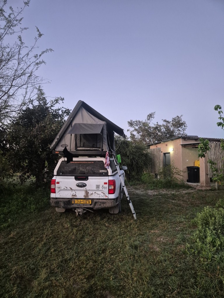 A 4x4 with a rooftop tent pitched at a Mababe River Lodge campsite at dusk