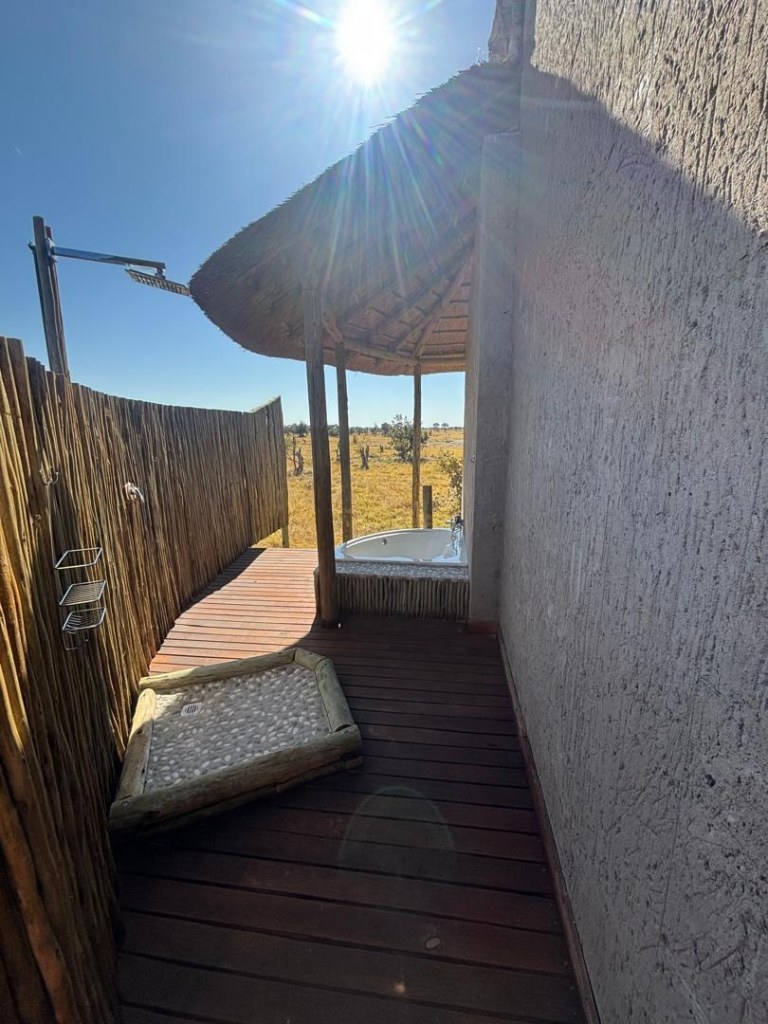 A private outdoor shower and sunken bath on a timber deck looking over the bush