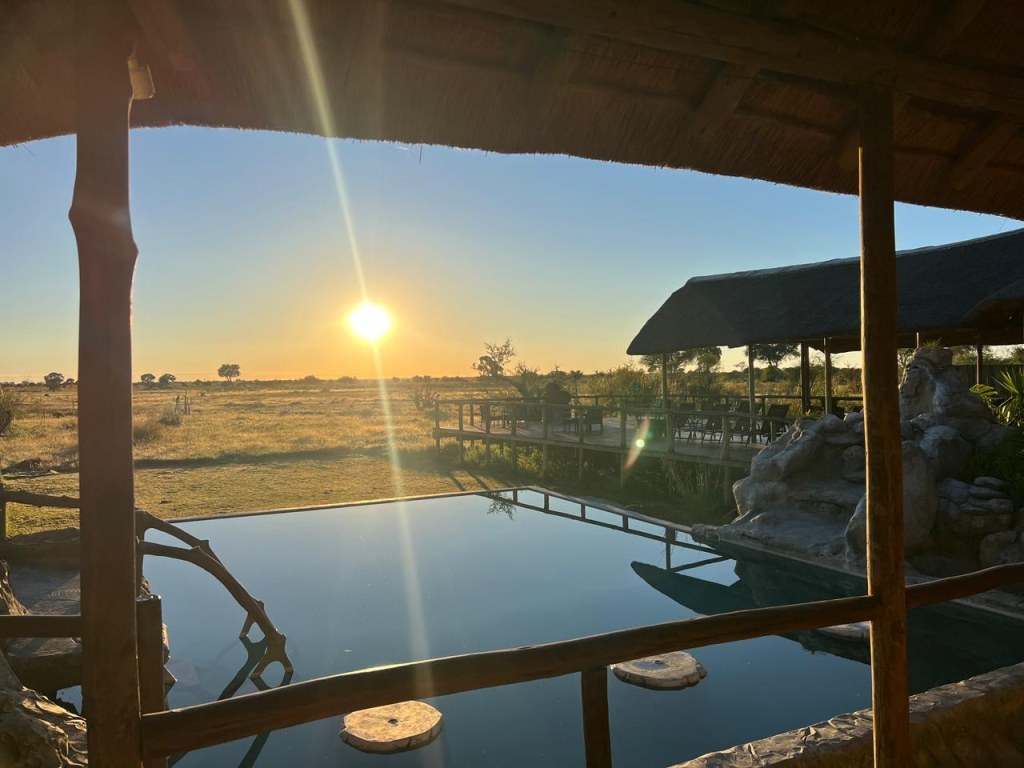 The infinity pool and deck at Mababe River Lodge at sunset, looking over the floodplain