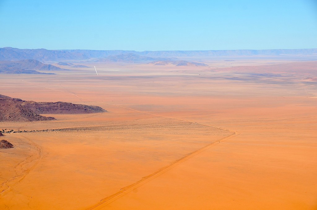Gravel road D707 through the Namib desert with mountains beyond