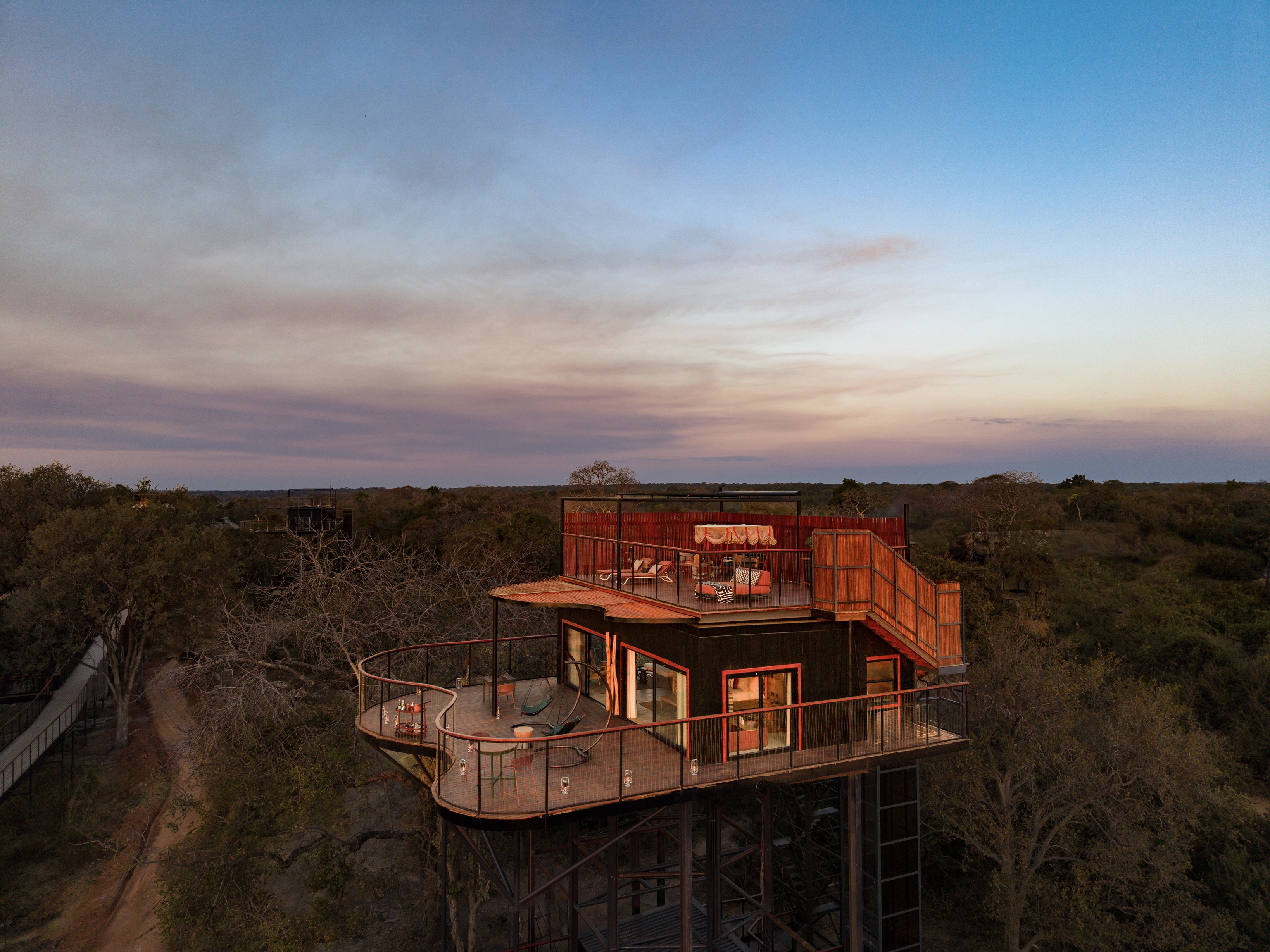 Anantara's tented camp on the Kafue River lit at dusk, seen from across the bush