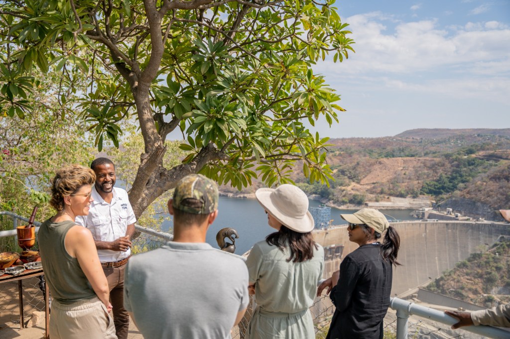 Guide and guests looking out over the Kariba Dam wall from a viewpoint above the lake